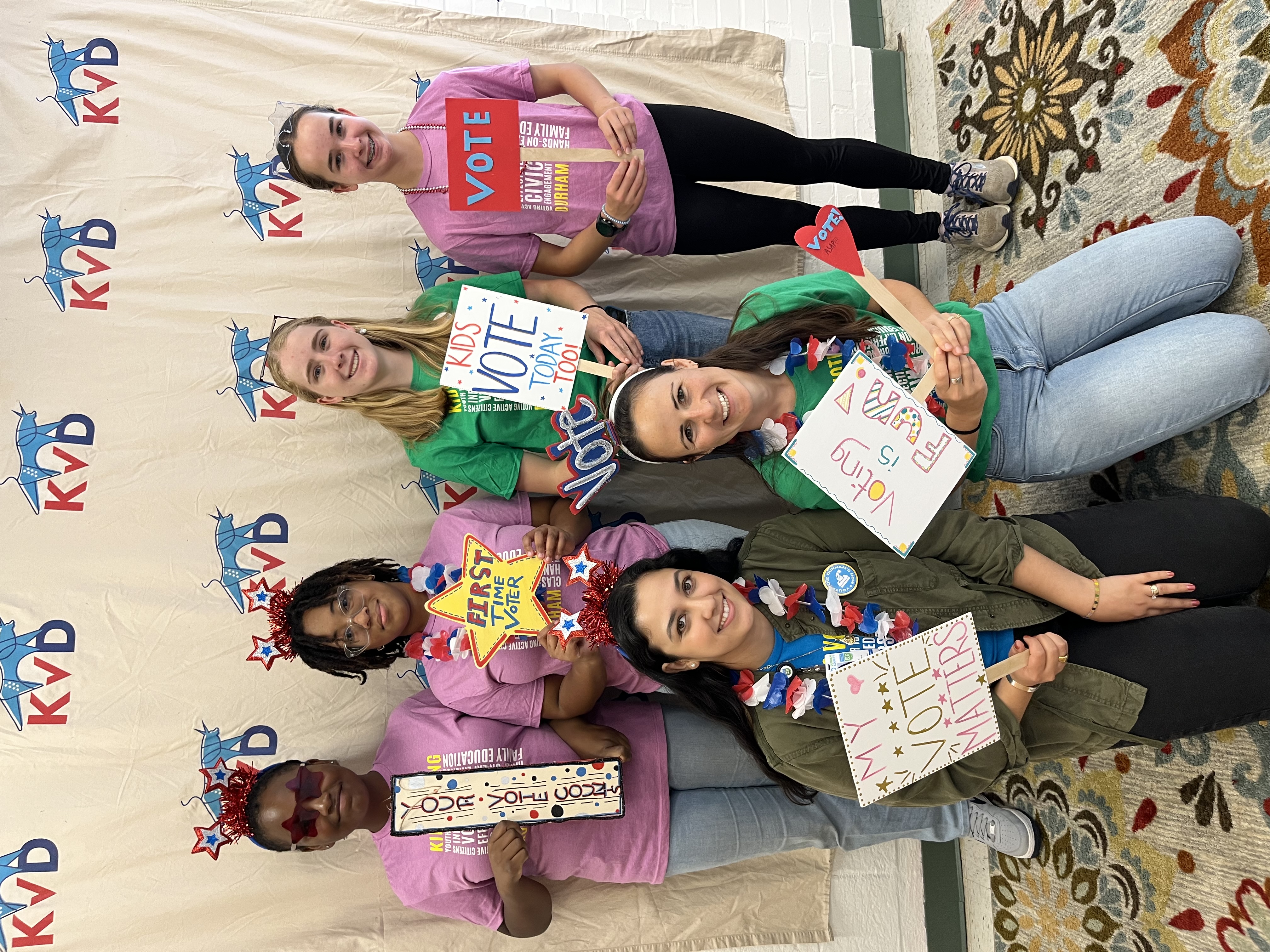A group of girls hold signs encouraging others to vote.